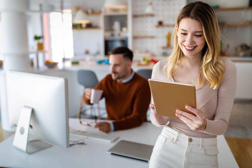 a woman holding a tablet and looking at a man in the background
